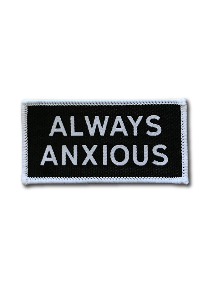 "Always Anxious" in white block text embroidered on black patch with white merrowed edge.  Art by Print Ritual.